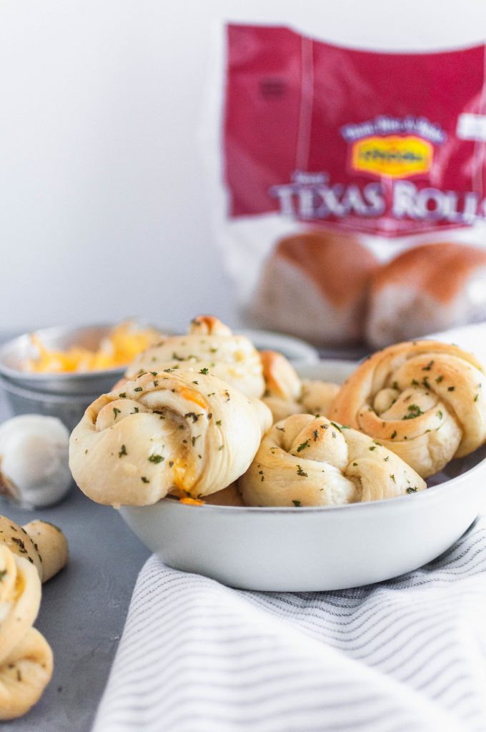 Make these simple, delicious, cheese stuffed Garlic Knots using Rhodes Bake-N-Serv Texas rolls for your next holiday dinner. Simple to make and taste homemade! Check out the step-by-step tutorial for these super simple rolls.