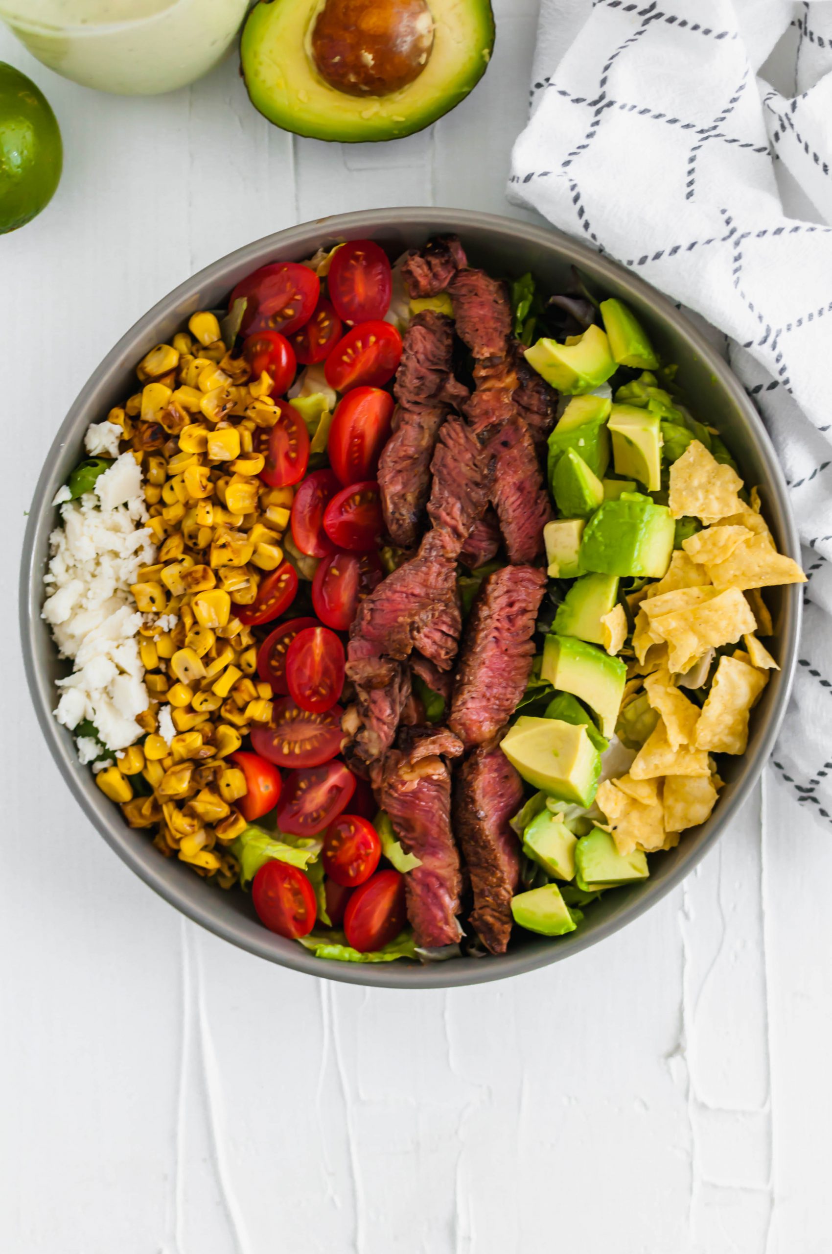 This Southwest Steak Salad is the ultimate summer salad. Packed with grilled steak, charred corn, avocado, crumbled queso fresco, tomatoes and crushed tortilla chips.