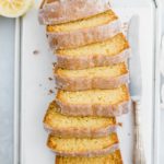 Sliced Starbucks lemon loaf arranged in a slight s shape with a decorative knife to the right and squeeze lemons in the top left corner.