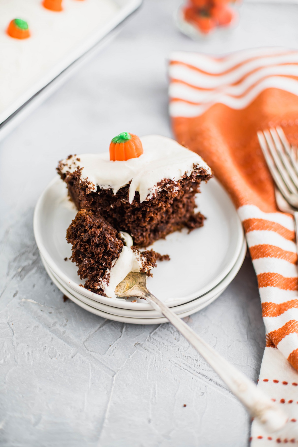 Slice of chocolate pumpkin cake on a small white plate with a bite on a fork.