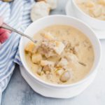 White bowl of cheeseburger soup with a spoonful being lifted out of the bowl.