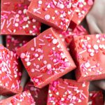 Close up of red velvet fudge piled into a dish lined with a pale pink cloth napkin.