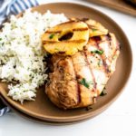 Grilled pineapple chicken and grilled pinapple rings on a plate with cilantro lime rice on the side.