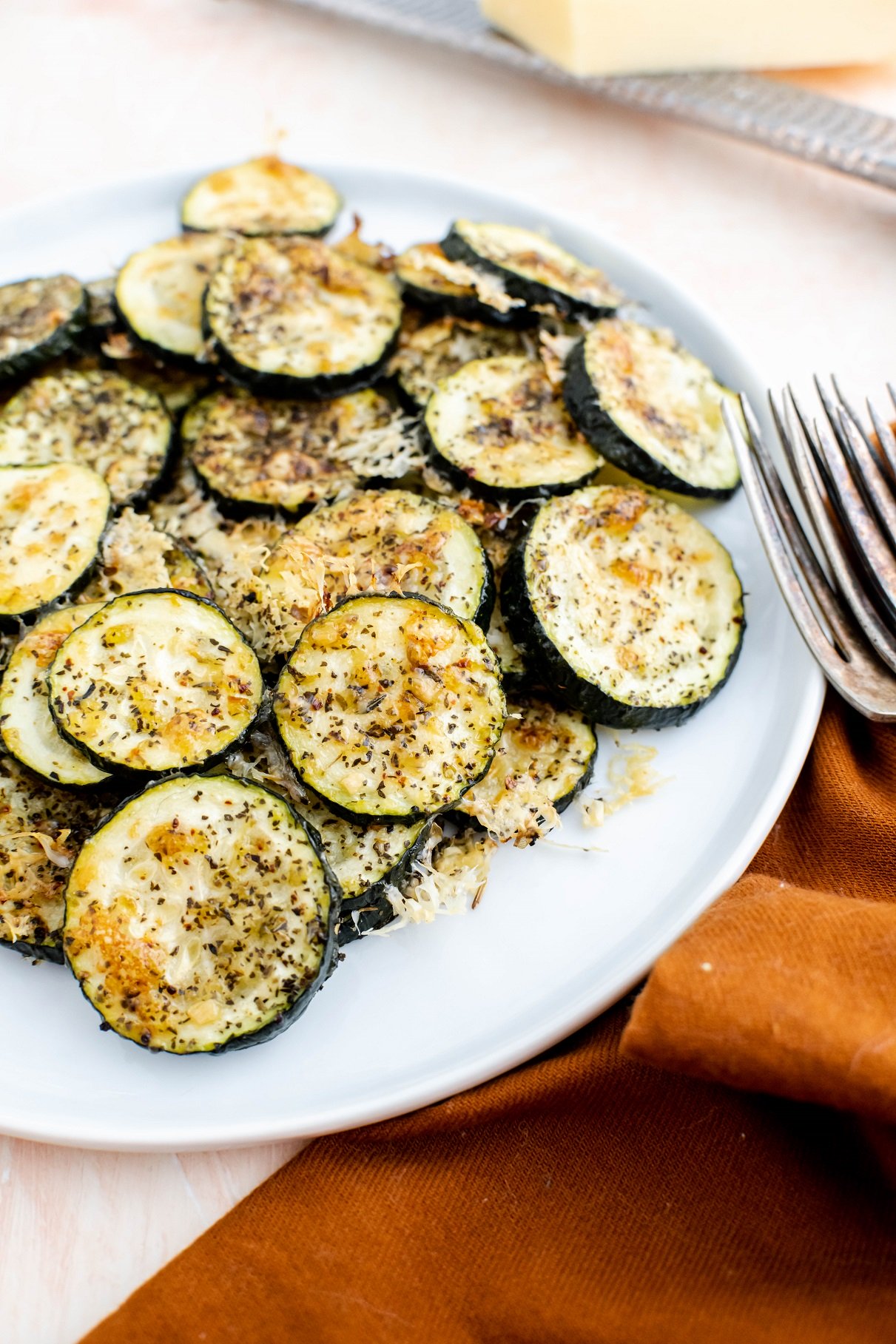 White plate filled with baked parmesan zucchini bites.