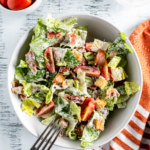 Bowl filled with blt salad. Fork leaning on the edge of the bowl.