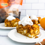 Three plates each with a portion of pumpkin bread pudding topped with fresh whipped cream.
