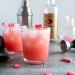 Two glasses of starburst cocktails with a shaker and a bottle of vodka in the background.