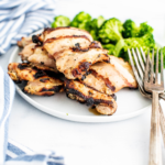 Grilled ranch chicken on a round white plate with steamed broccoli.