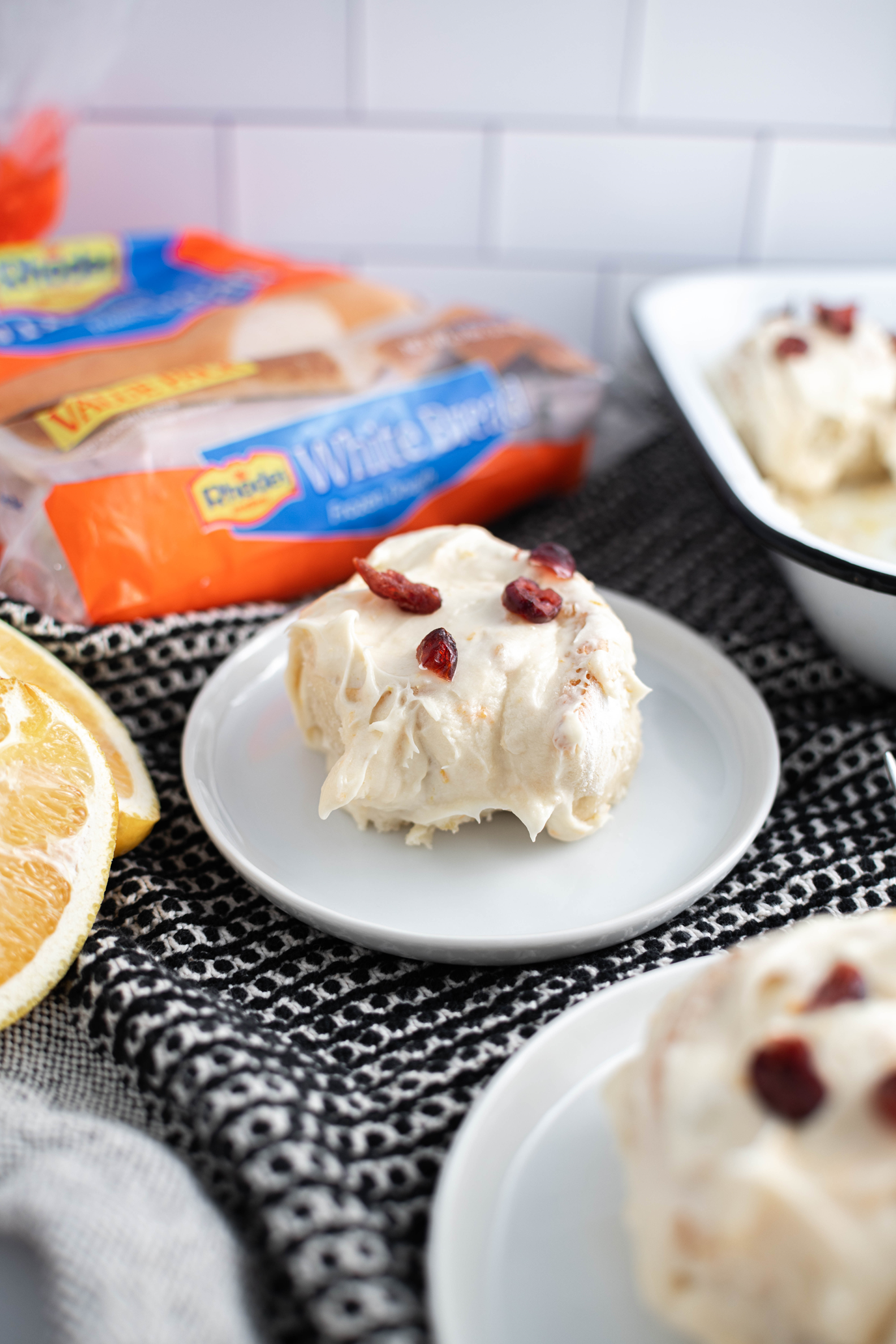 Orange Cranberry Roll on a round white plate with Rhodes bread dough package in the background.