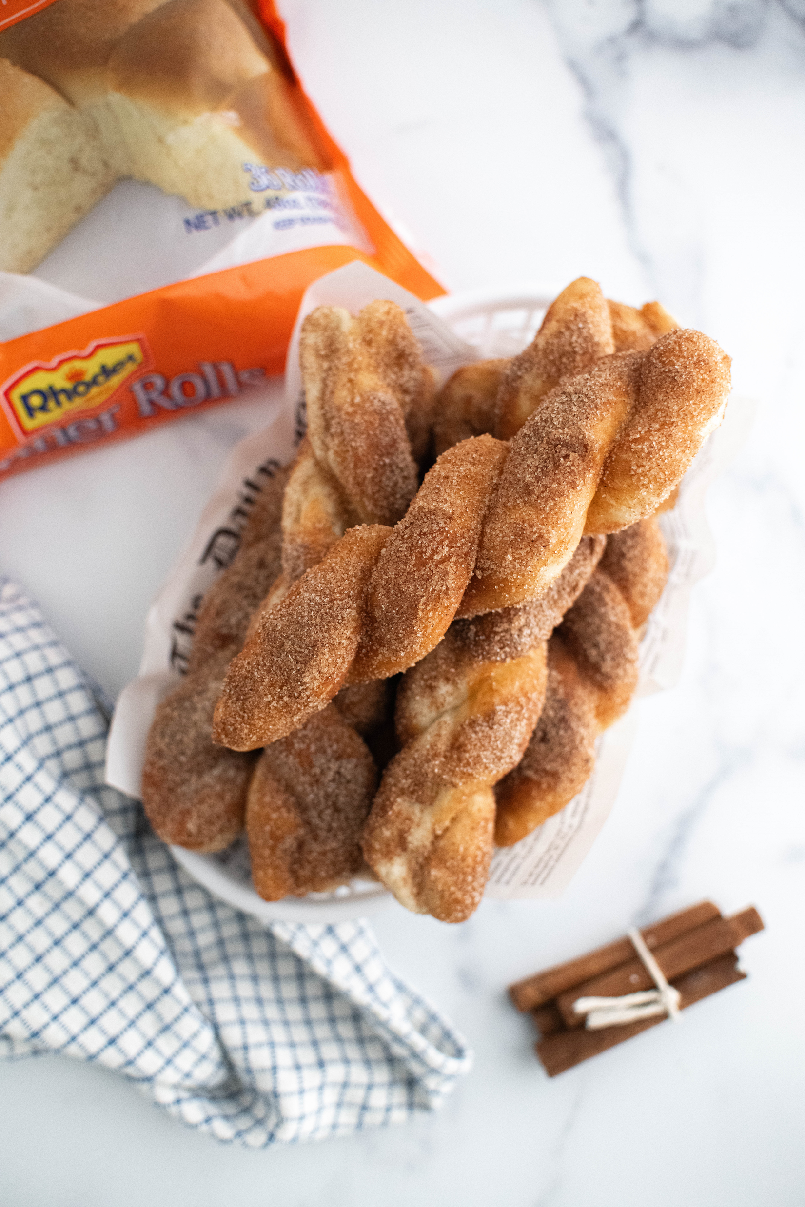 White plastic basket lined with newspaper filled with cinnamon twists.